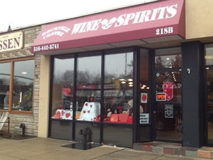 The image shows a storefront with a sign reading  Wine   Spirits  and a large window displaying various items, including bottles and decorative items, with a clear glass door.